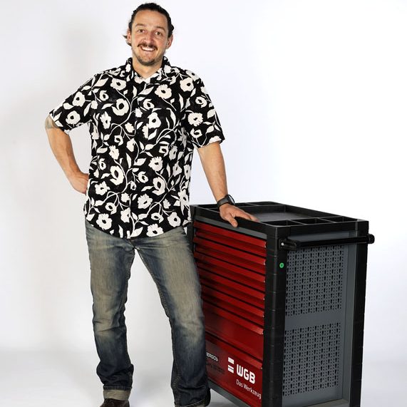 Motorradgutachter Schiebel Ein Motorradgutachter steht neben einer geöffneten Werkstattkiste. Er blickt aufmerksam auf ein Motorrad bereit für ein Kfz-Gutachten